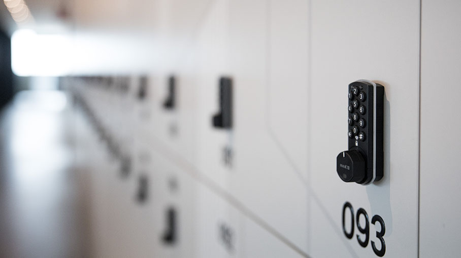 A close-up of a digital locker lock with the number "093" visible, set against a row of sleek, modern lockers in a bright space.
