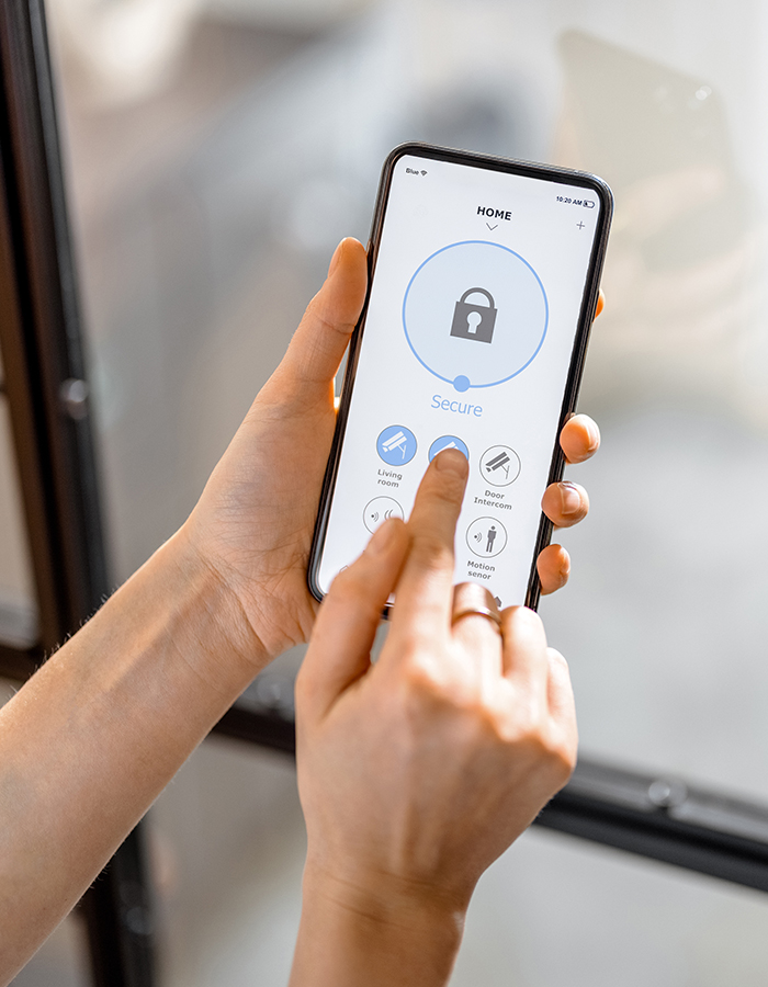 A person using a smartphone app to manage home security features, including locking doors and adjusting motion sensors.